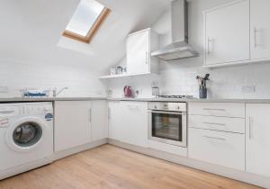 a kitchen with white cabinets and a washer and dryer at High Street Apartment in Edinburgh