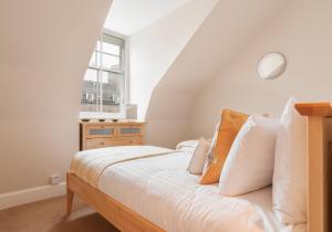 a bedroom with a bed with white sheets and a window at High Street Apartment in Edinburgh