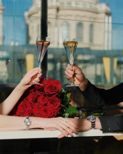 two people holding champagne glasses in front of a bouquet of roses at Aria Hotel Budapest by Library Hotel Collection in Budapest