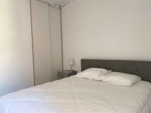 1 dormitorio con 1 cama con sábanas blancas y lámpara en Appartement Balaruc-les-Bains, 2 pièces, 2 personnes - FR-1-553-214, en Balaruc-les-Bains