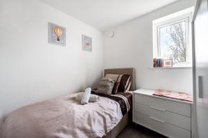 a bedroom with a bed and a dresser and a window at Modern Apartment Near Train Station in Ipswich