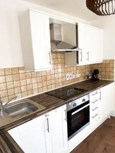 eine Küche mit weißen Schränken und einem Waschbecken in der Unterkunft London Stylish 1 Bedroom Apartment in London