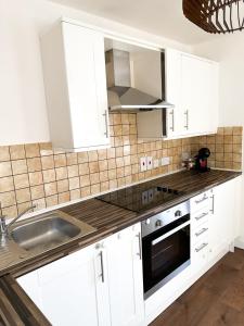 a kitchen with white cabinets and a sink at London Stylish 1 Bedroom Apartment in London