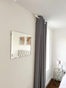 um quarto com cortinas cinzentas e um espelho em London Stylish 1 Bedroom Apartment em Londres