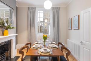a dining room with a table and chairs and a fireplace at Spacious Private home with King sized bed and Garden newly renovated in London