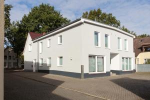 a white house on the side of a street at CABANA Kreyenbrück - Maisonette Apartments - Parkplatz - Nähe Klinikum - WLAN - Netflix in Oldenburg