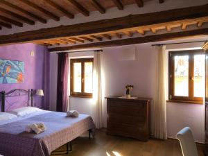 a bedroom with a bed and a dresser and two windows at Guest-House Del Corso in Montepulciano