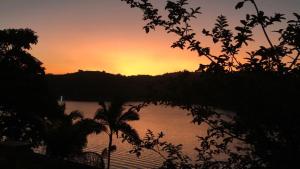 una puesta de sol sobre un cuerpo de agua con un árbol en Chácara Morada do Sol - (pé na represa) en Igaratá