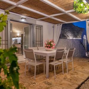 einen weißen Tisch mit Stühlen und eine Vase mit Blumen darauf in der Unterkunft TRULLO TIPOTA with private pool in Ceglie Messapica