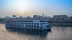 阿斯旺Steigenberger Royale Nile Cruise - Every Thursday from Luxor for 07 & 04 Nights - Every Monday From Aswan for 03 Nights的水面上的游轮,以城市为背景