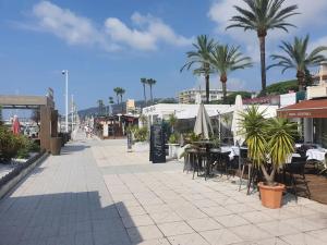 a street with tables and chairs and palm trees at Bas de villa cosy Juan les Pins avec jardin in Juan-les-Pins