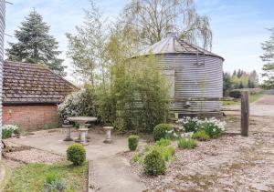 un jardín con un tanque de agua y un baño de aves en The Corn Bin en Sedlescombe