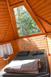 Cama en habitación de madera con ventana en Camping le Colorado en Rustrel