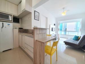 a kitchen with a table and a yellow chair in a room at Piscina a beira-mar, tranquilidade e qualidade no melhor de BC in Balneário Camboriú