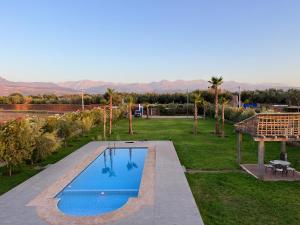 a swimming pool in the middle of a field with a yard at Maison Dar Zarka in Aghmat