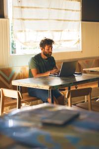 um homem sentado numa mesa com um laptop em Hostel Like Quijote em San Carlos de Bariloche