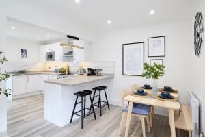 a white kitchen with a table and stools in it at The Castleman in Ferndown