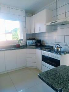 a kitchen with white cabinets and a stove top oven at SHOW RURAL 2024- casa com ar e piscina in Cascavel