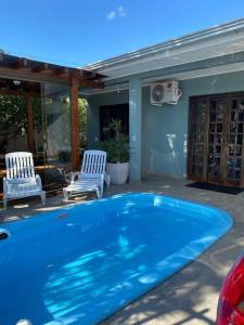 a blue swimming pool in a yard with two chairs at SHOW RURAL 2024- casa com ar e piscina in Cascavel