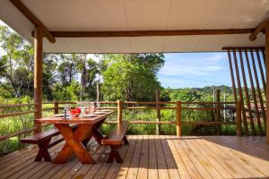 una terraza de madera con mesa y bancos. en Quartos Do Vilarejo, en Trancoso