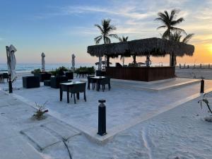 Palm House في صلالة: بار على الشاطئ مع طاولات وكراسي على الشاطئ
