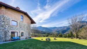 a stone house with a grassy yard next to a building at Soloandie Casa rural in Zeanuri