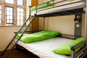 a bunk bed with green pillows and a ladder at YHA Grinton Lodge in Reeth