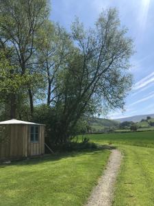 a small shed in a field with a dirt road at Wye Glamping in Velindre