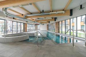 a swimming pool in a building with windows at Bel Mare Modern Apartment with Balcony by Renters in Międzyzdroje