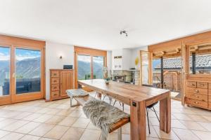 a kitchen with a wooden table and some windows at Luxury Chalet: Alpine Magic with Terrace Views in Crans-Montana