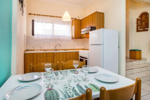 a kitchen with a table with chairs and a white refrigerator at Studios Anagnostou in Skala Marion