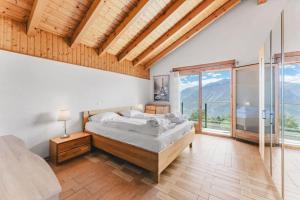 a bedroom with a large bed and a large window at Luxury Chalet: Alpine Magic with Terrace Views in Crans-Montana