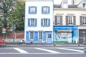 un edificio blu e bianco su una strada cittadina di Le Duplex Troyen - 5 min Hypercentre - Ideal Groupe - Parking Gratuit a Troyes