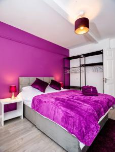 a purple bedroom with a large bed with a purple blanket at 3-Bed Apartment Central London - 15 Mins walk to Kings Cross by Seren Short Stays in London