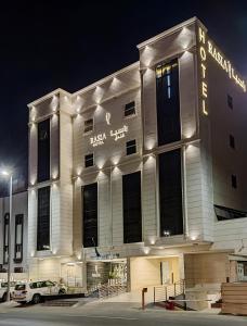 Un grand bâtiment blanc avec des lumières allumées la nuit dans l'établissement Rasia Hotel Jeddah, à Djeddah