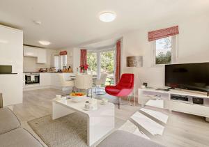 a large white living room with a red chair at Sennen - St Ives in Carbis Bay