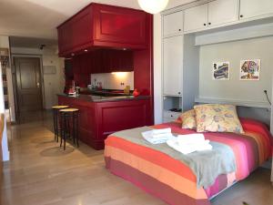 a bedroom with a red bed and a kitchen at Loft acogedor con terraza y parking en el centro in Huesca