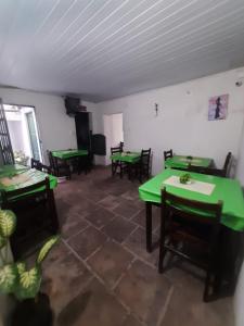 un comedor con mesas verdes y sillas en Pousada do Guerreiro, en Cachoeira