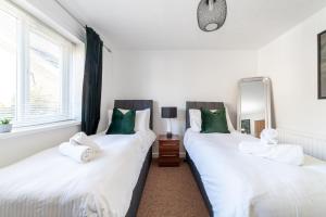 two beds in a room with white sheets and green pillows at Mead Court Estate Apartment in Egham By Rent Firmly Short Lets Serviced Accommodation With Free On-Site Parking in Egham