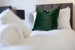 a bed with white pillows and a green pillow at Mead Court Estate Apartment in Egham By Rent Firmly Short Lets Serviced Accommodation With Free On-Site Parking in Egham