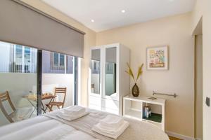 a bedroom with a bed and a balcony with a table at Bougainvillea House in Faro
