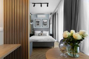 Elite Apartments Chlebova Premium في غدانسك: غرفة نوم بسرير وطاولة مع إناء من الزهور