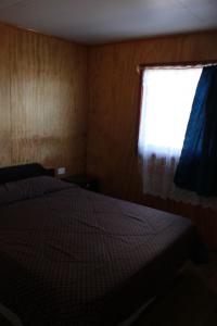 1 dormitorio con cama y ventana en Cabañas y Agroturismo RanchoJyC, en Teodoro Schmidt