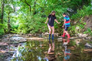 two people walking across a stream in a river at Wye Glamping in Velindre