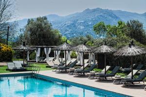 uma piscina com espreguiçadeiras e guarda-sóis em Suites Natura Mas Tapiolas em Santa Cristina d'Aro