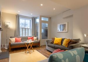 a living room with two couches and a table at Fern Cottage - Whitstable in Whitstable