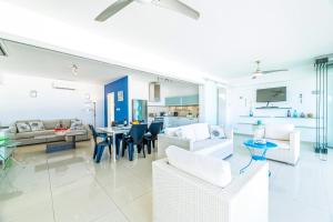 a living room with white furniture and a dining room at Silver Sands Penthouse in Protaras