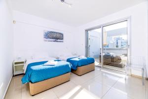 two beds in a white room with a window at Silver Sands Penthouse in Protaras