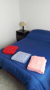 a blue bed with three pillows on top of it at Sendero Patagonico in Las Grutas