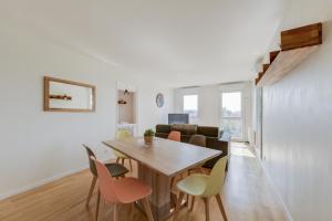 a dining room and living room with a wooden table and chairs at Chic apartment with superb view of the eiffel tower in Saint-Denis